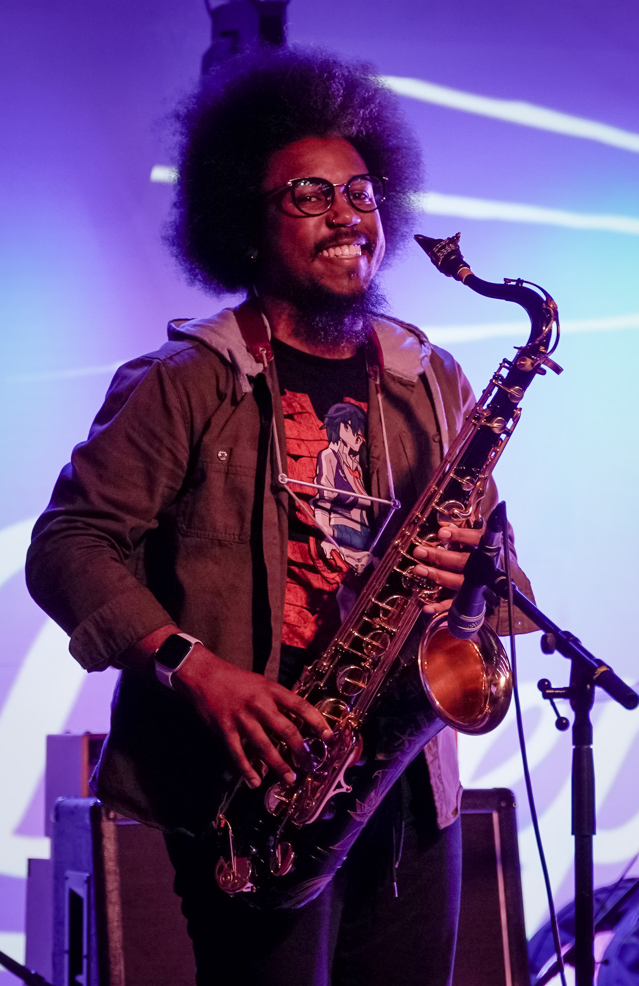 A musician on stage holding a saxophone and smiling 