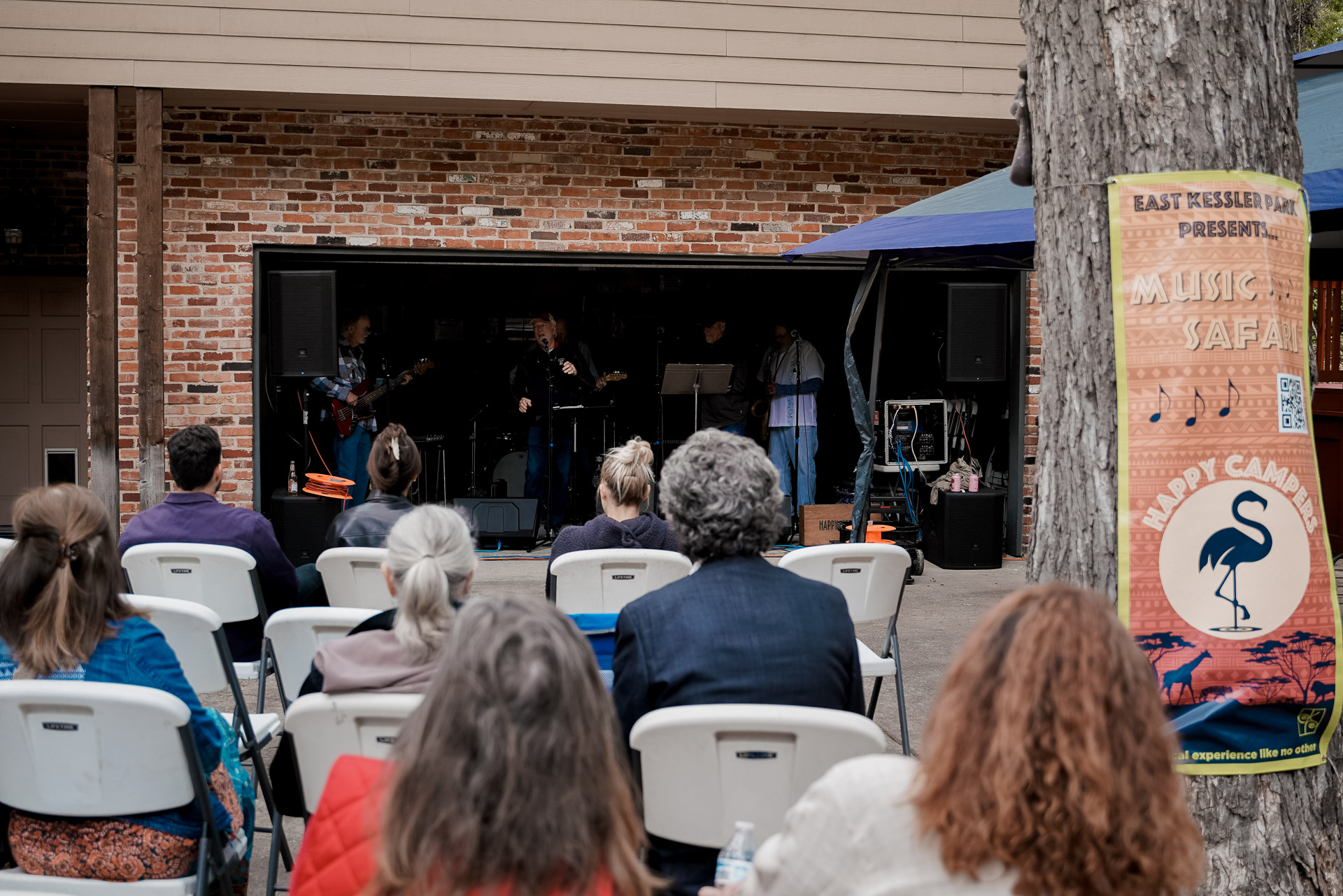 A band performing inside a garage with a seated audience in front of it