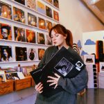 A woman stands inside Spinster Records, holding copies of a Taylor Swift LP set