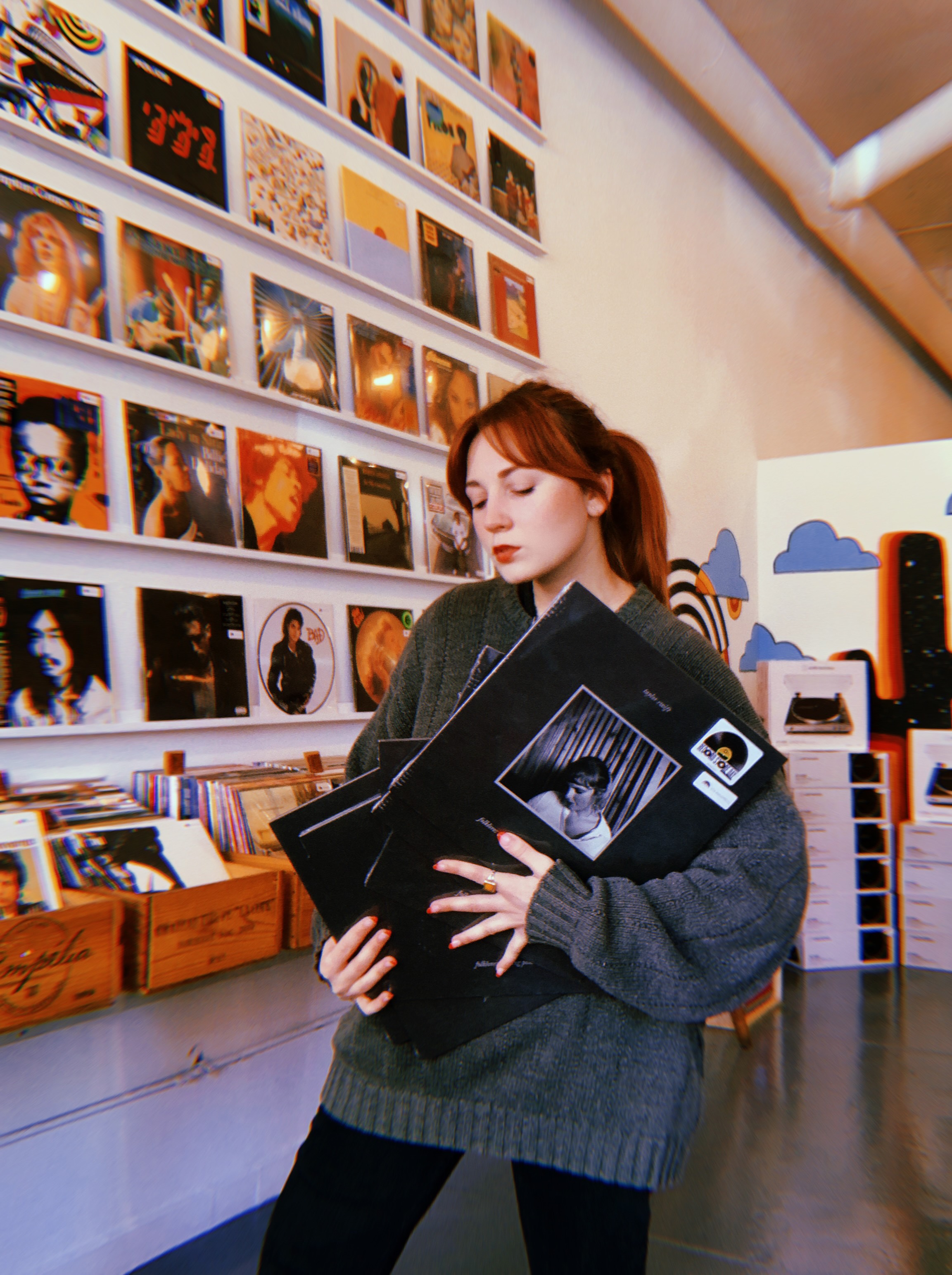 A woman stands inside Spinster Records, holding copies of a Taylor Swift LP set