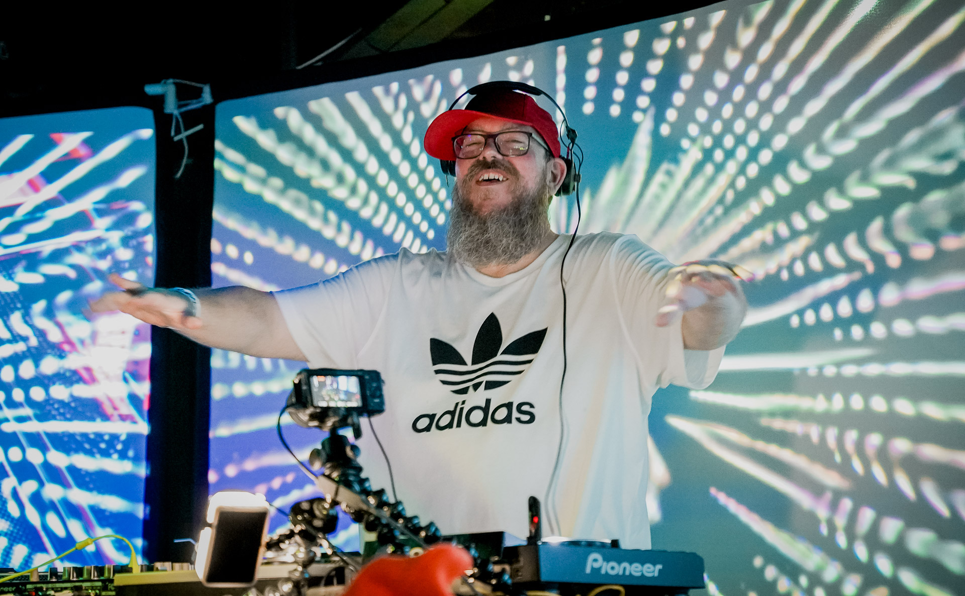 A dj smiling with his hands up