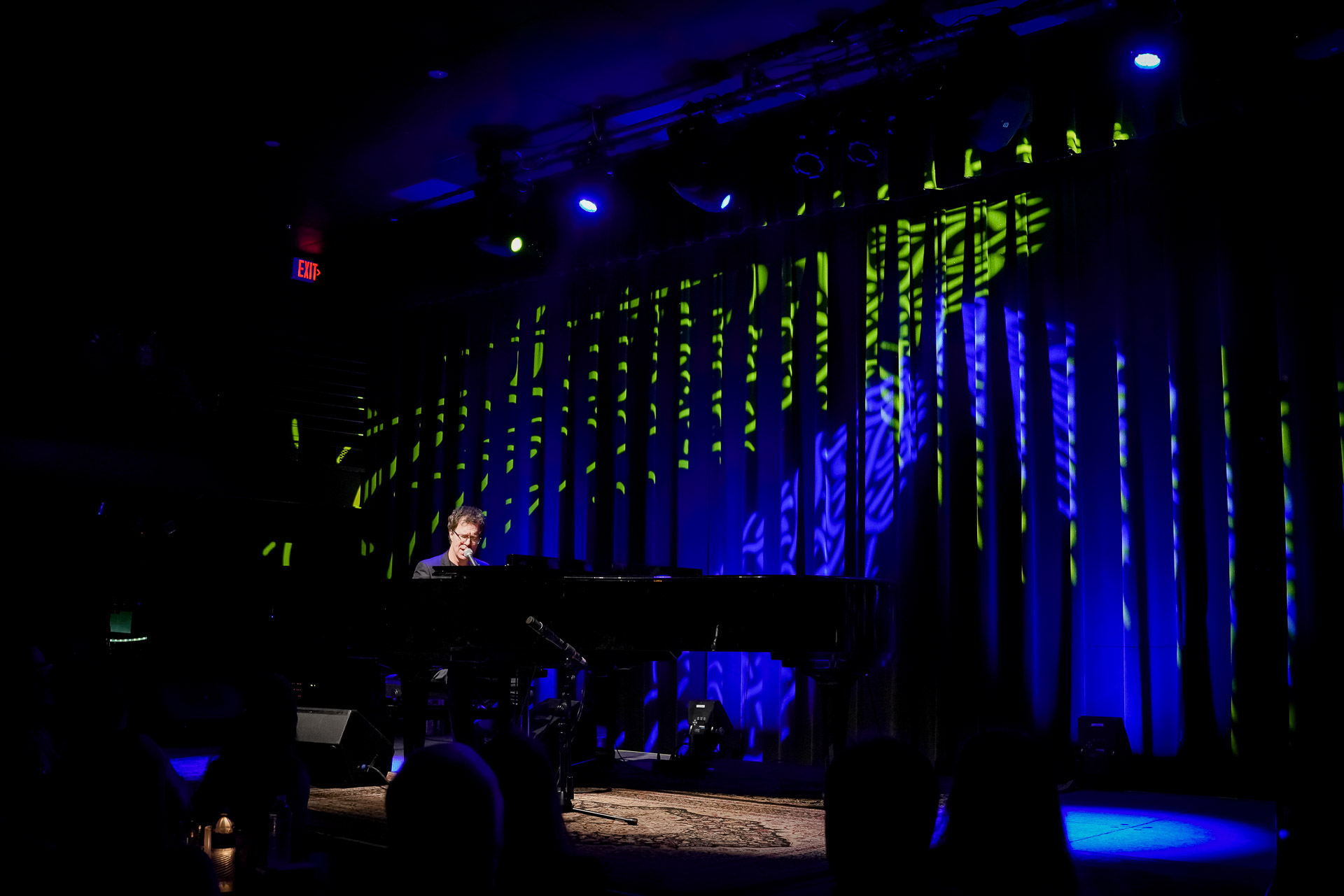A man playing piano on stage, wider shot