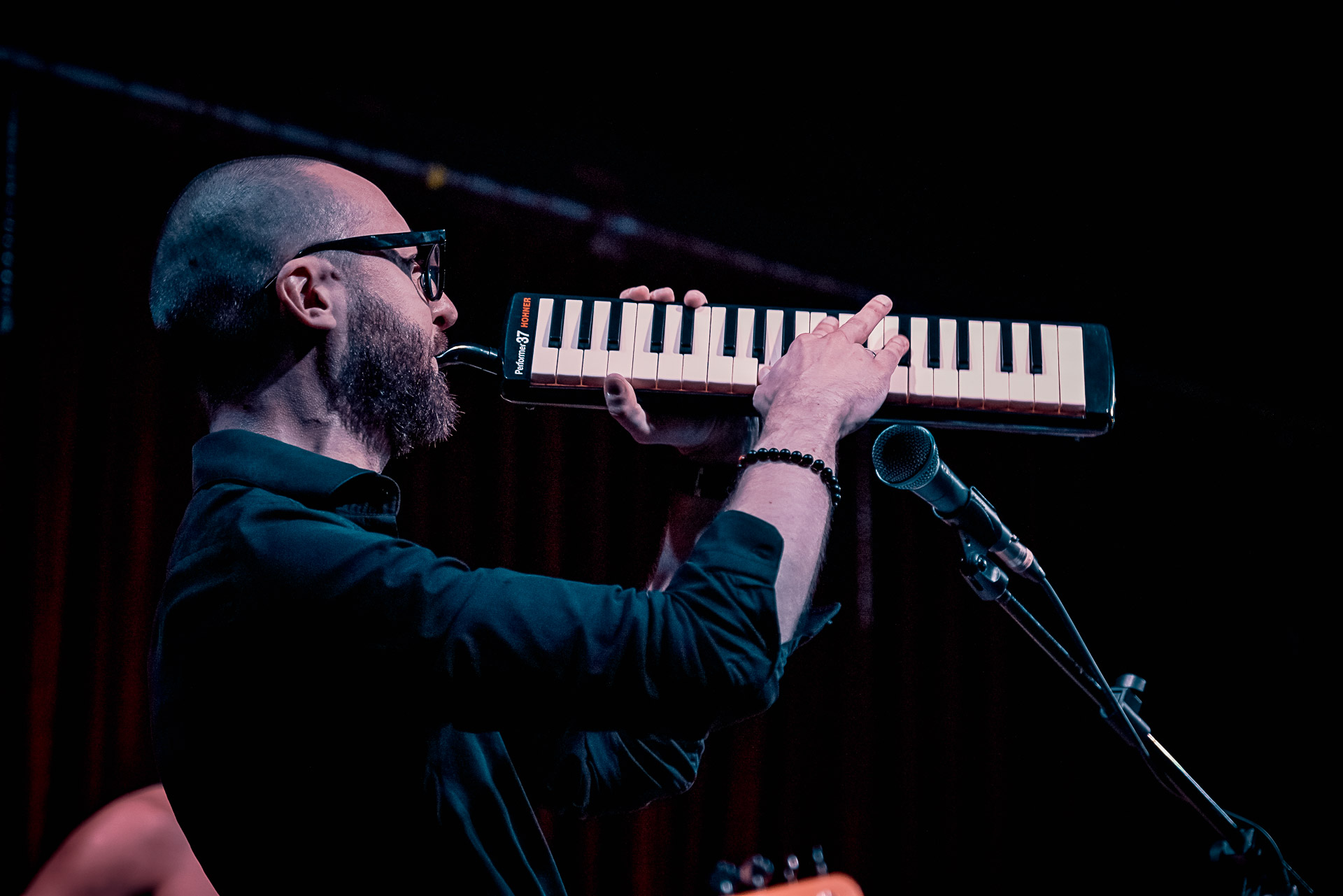 A man playing melodica on stage