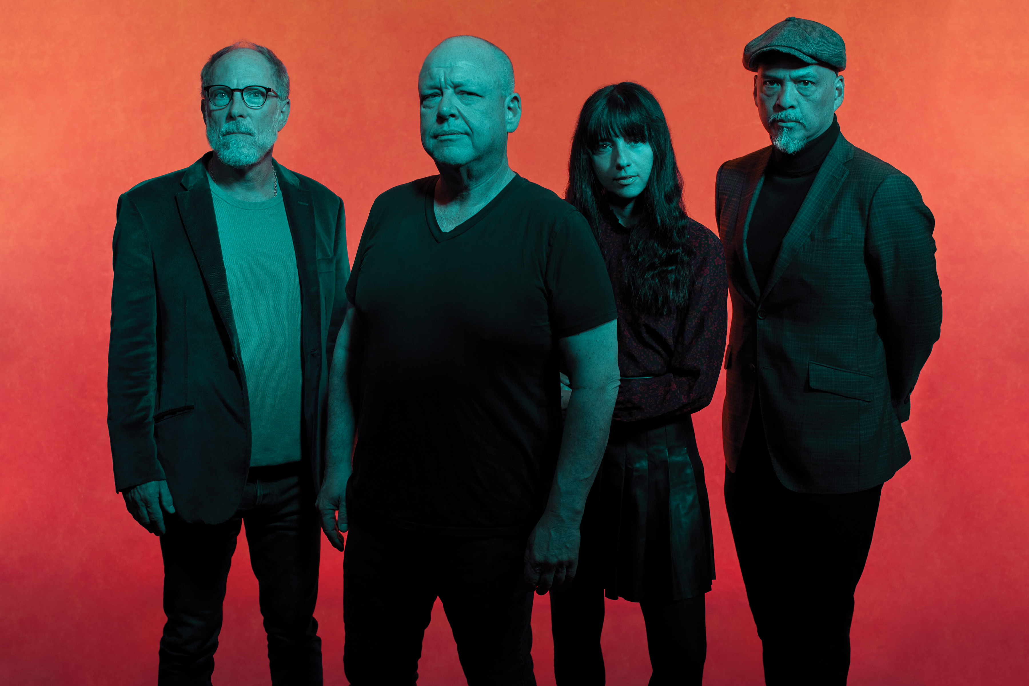 Against a red backdrop, Pixies face the camera