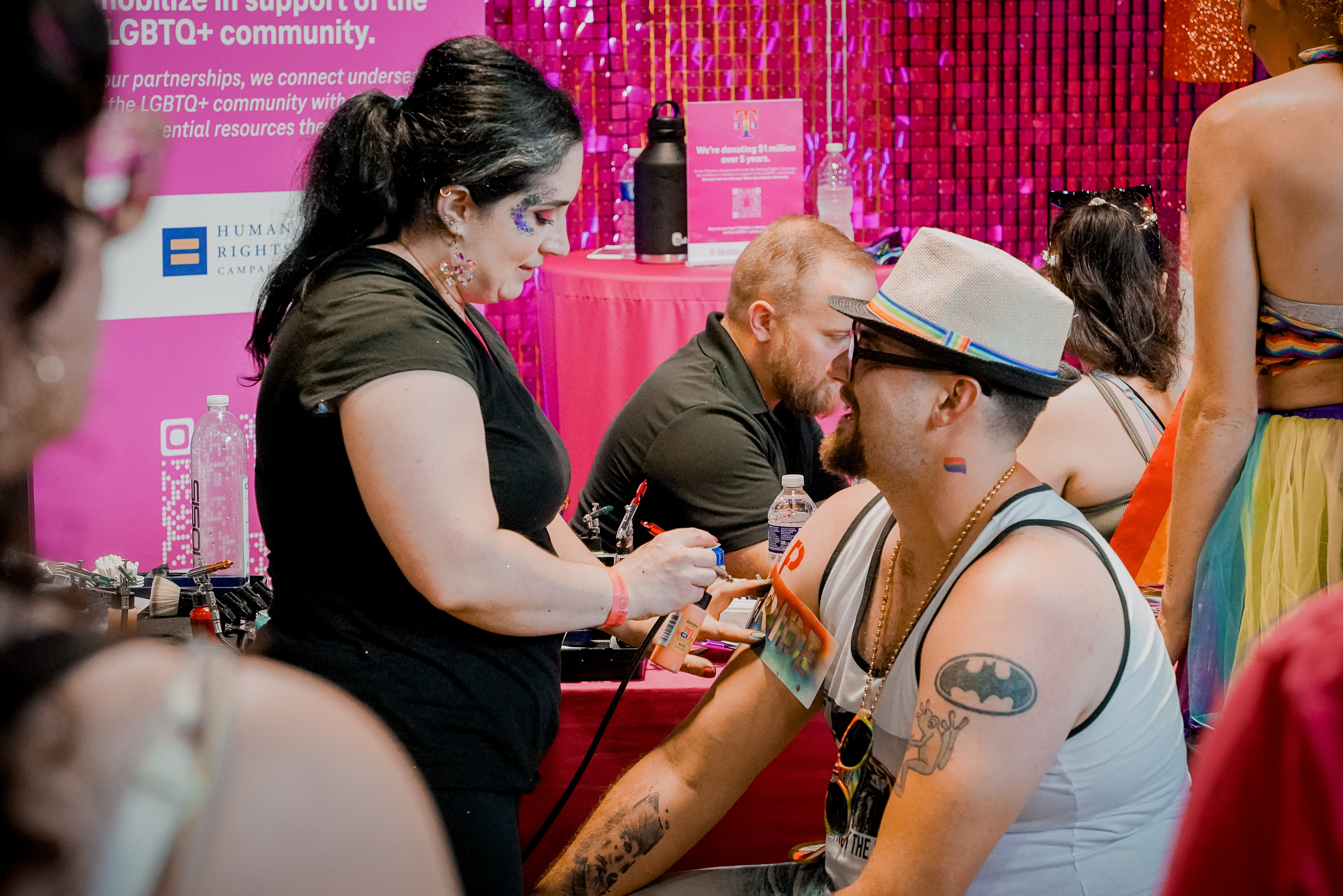 A person giving another person an airbrush tattoo