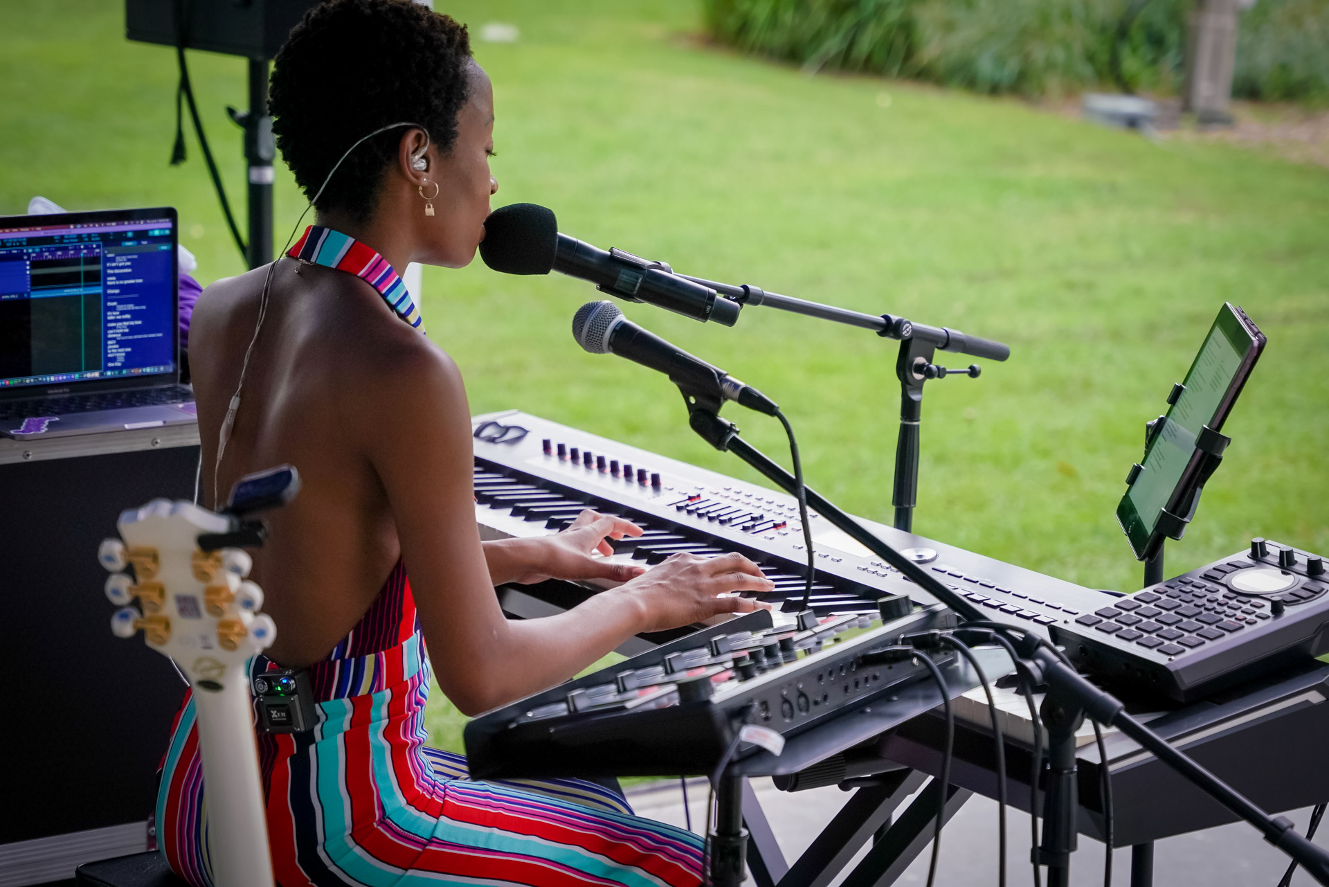 A musician playing on a keyboard, singing, and a looper to her right side