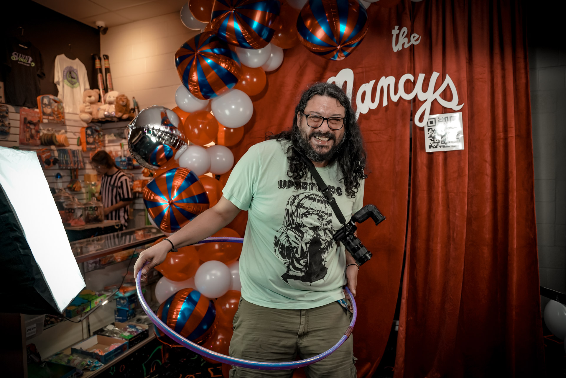 A guy in front of a backdrop with balloons, hula-hooping