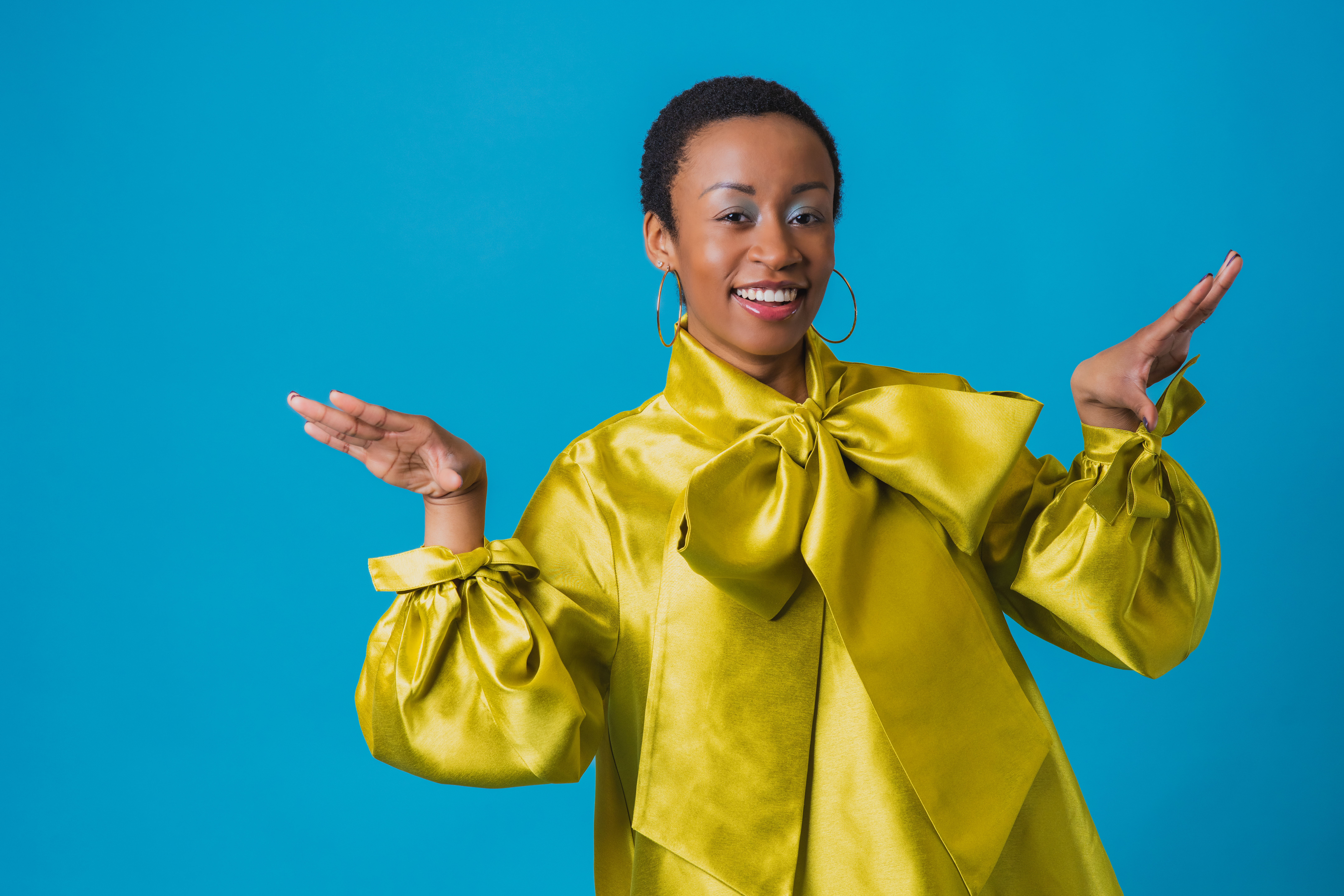 Wearing a yellow shirt, Damoyee poses in front of a blue backdrop