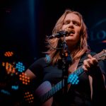 A musician playing guitar and singing on stage