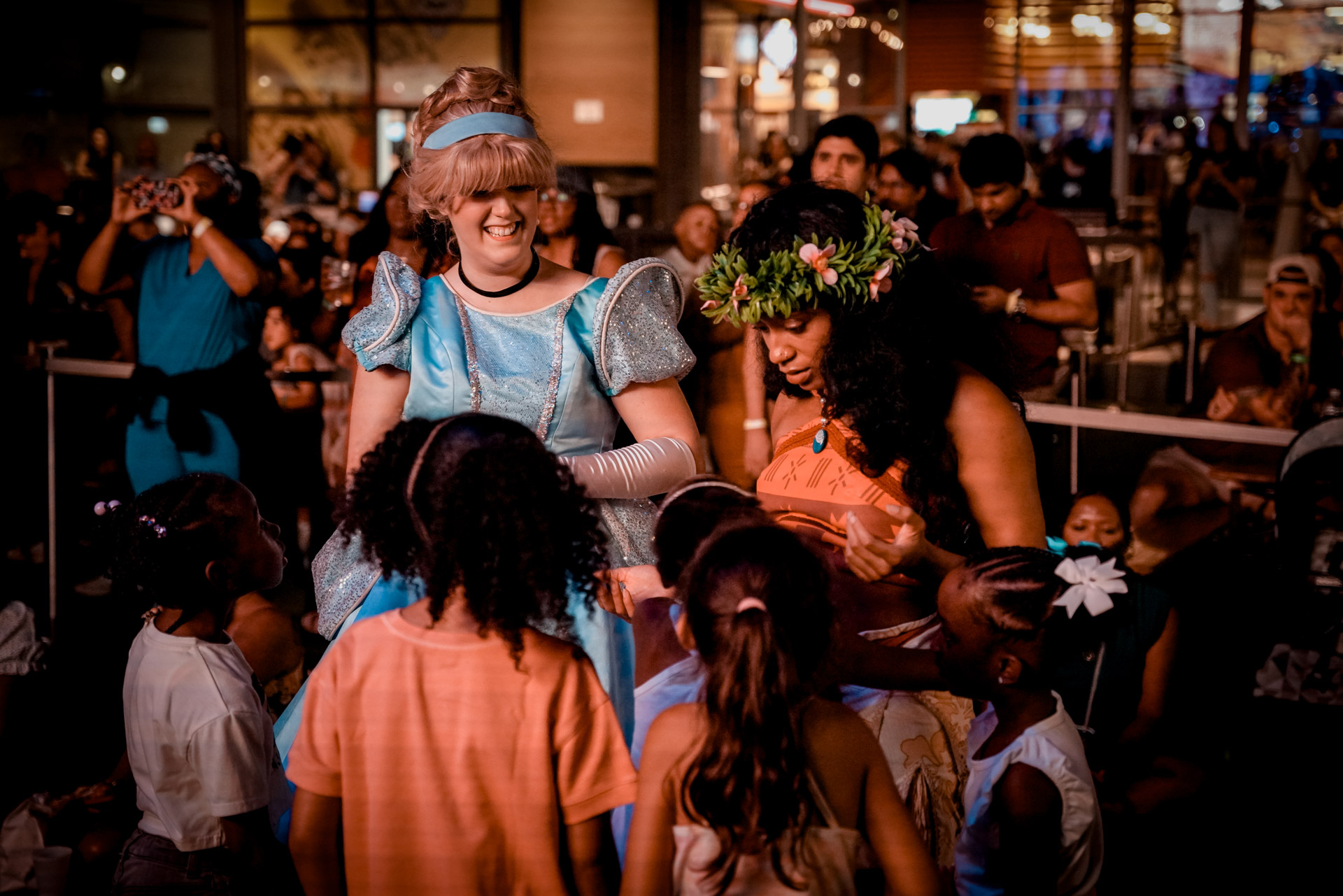 Kids gathered around two women dressed as Disney princesses
