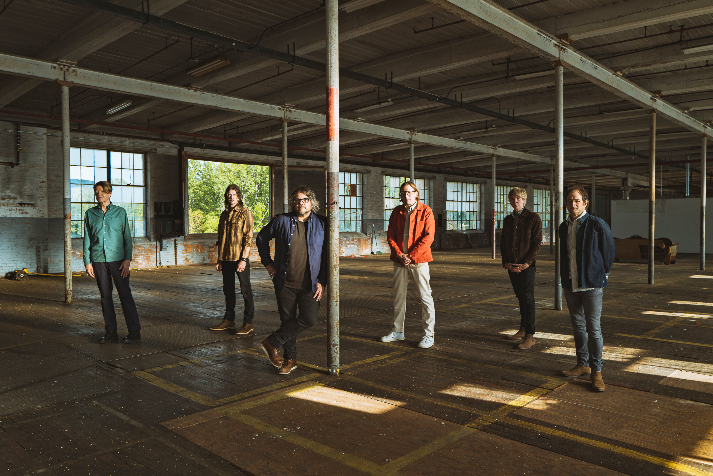 Standing inside an industrial space, Wilco faces the camera