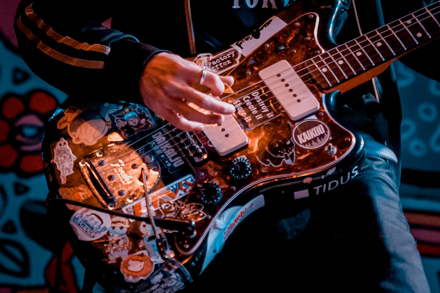 A close up of a guitar with many stickers on it
