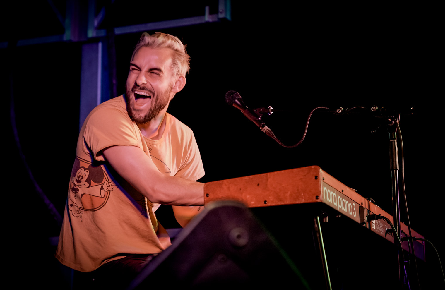 A musician playing keyboard and laughing on stage