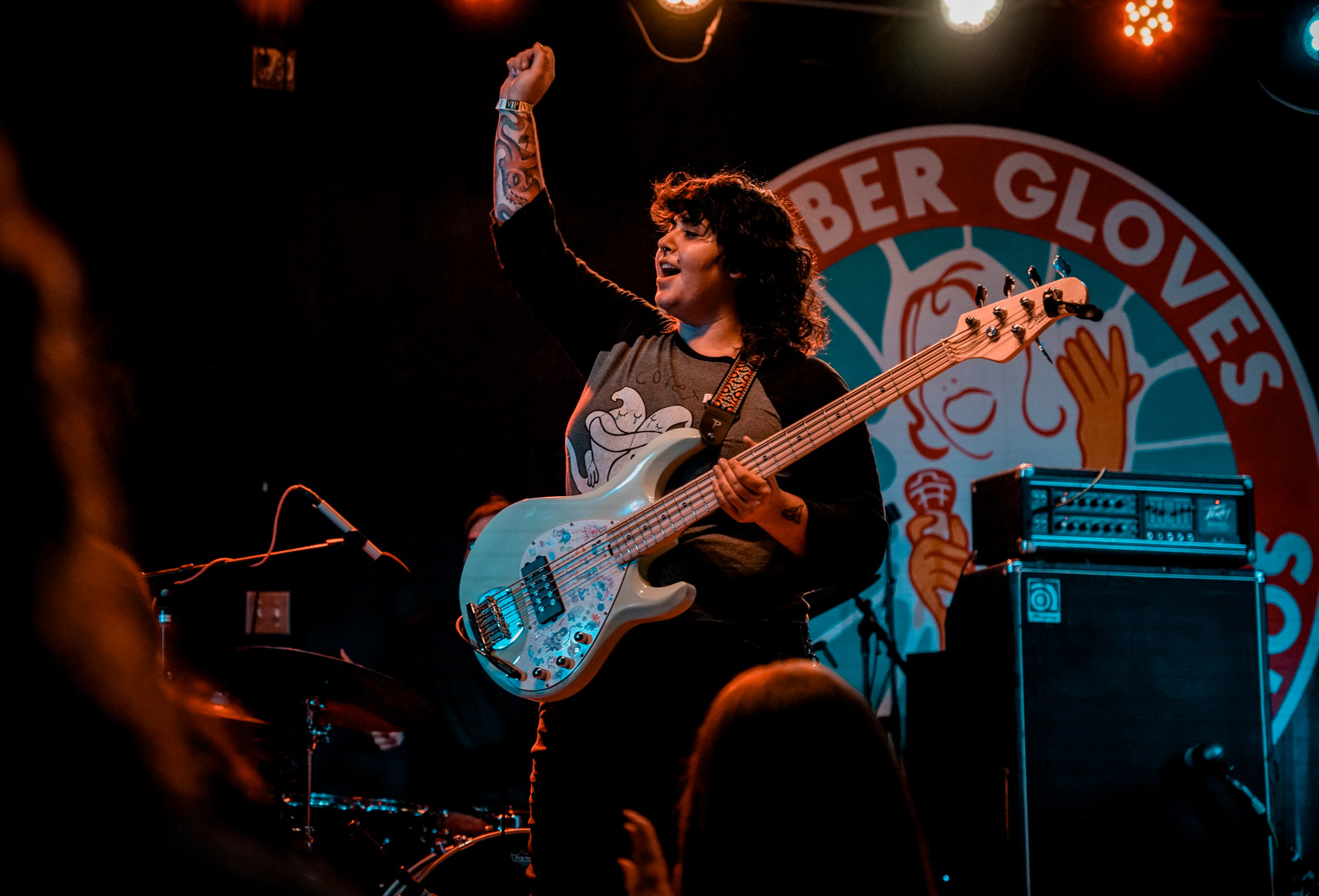 A musician on stage with a bass guitar, and her hand in the air