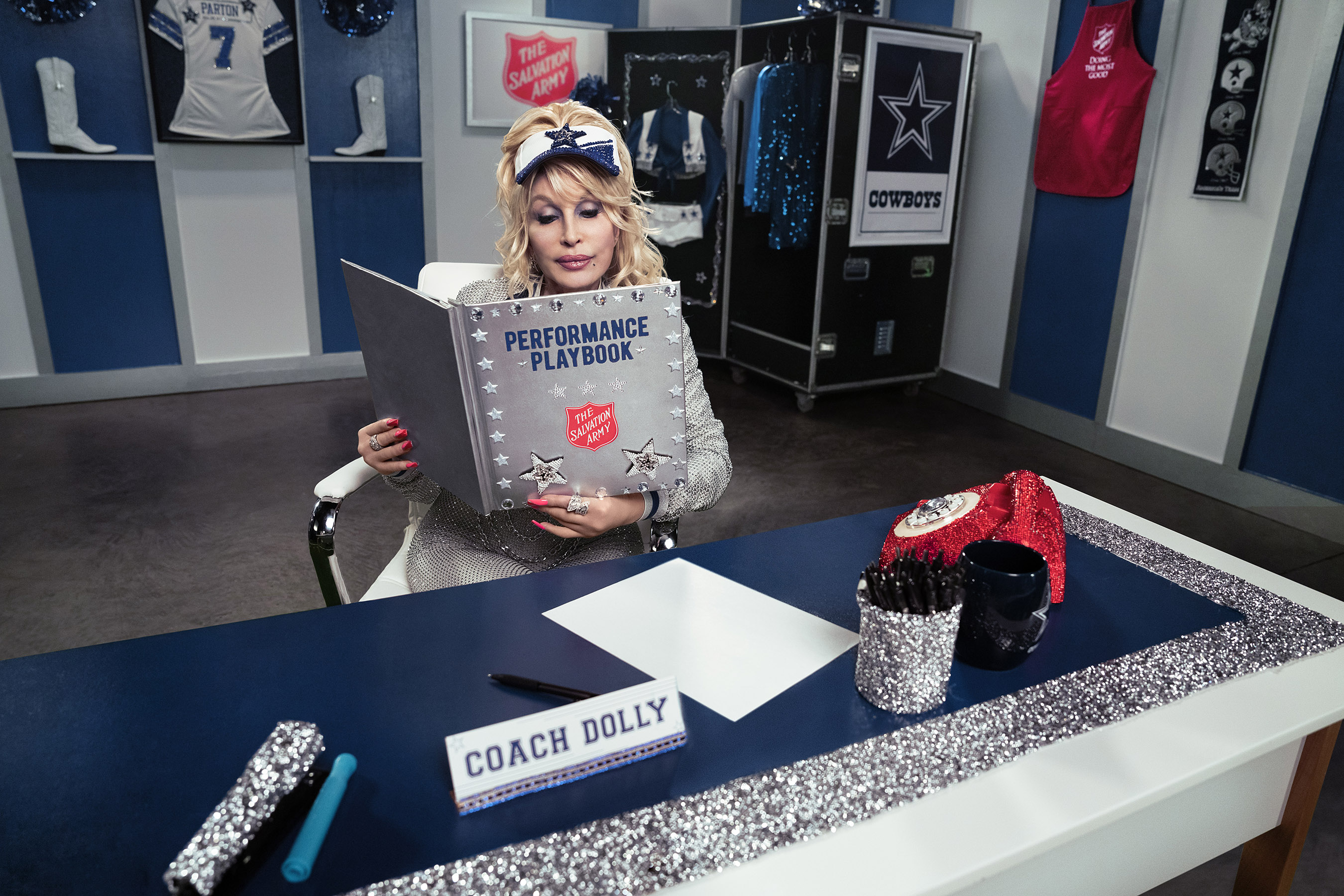 Dolly Parton reviews a playbook in the Dallas Cowboys locker room