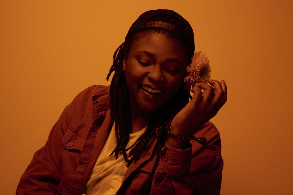 Joy Oladokun smiles and holds a flower