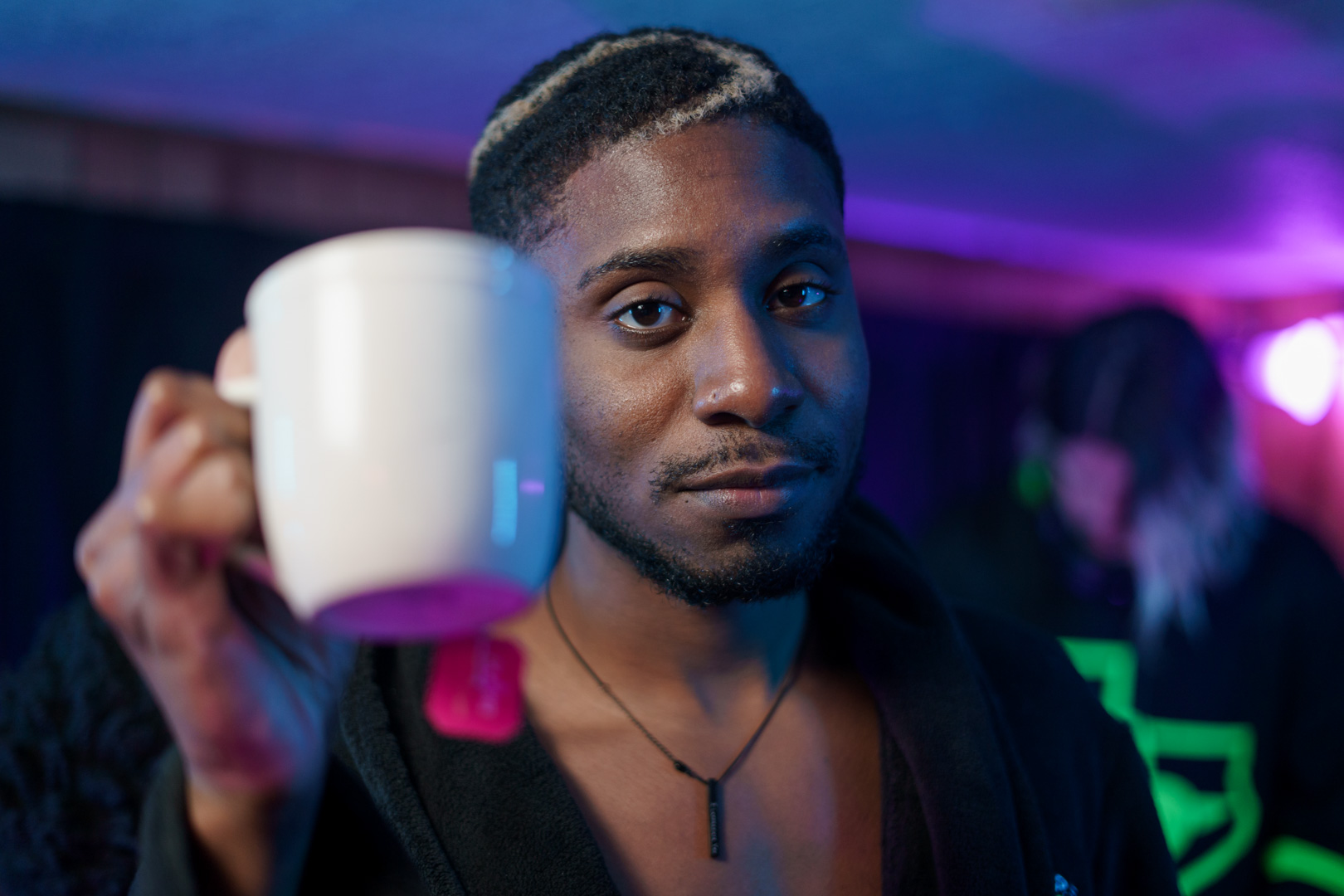 A young man looking into camera holding tea cup