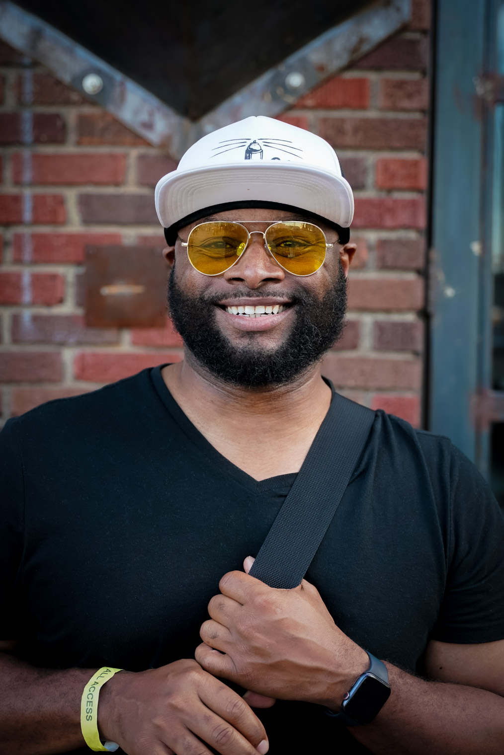 A man looking into camera smiling wearing yellow tinted glasses