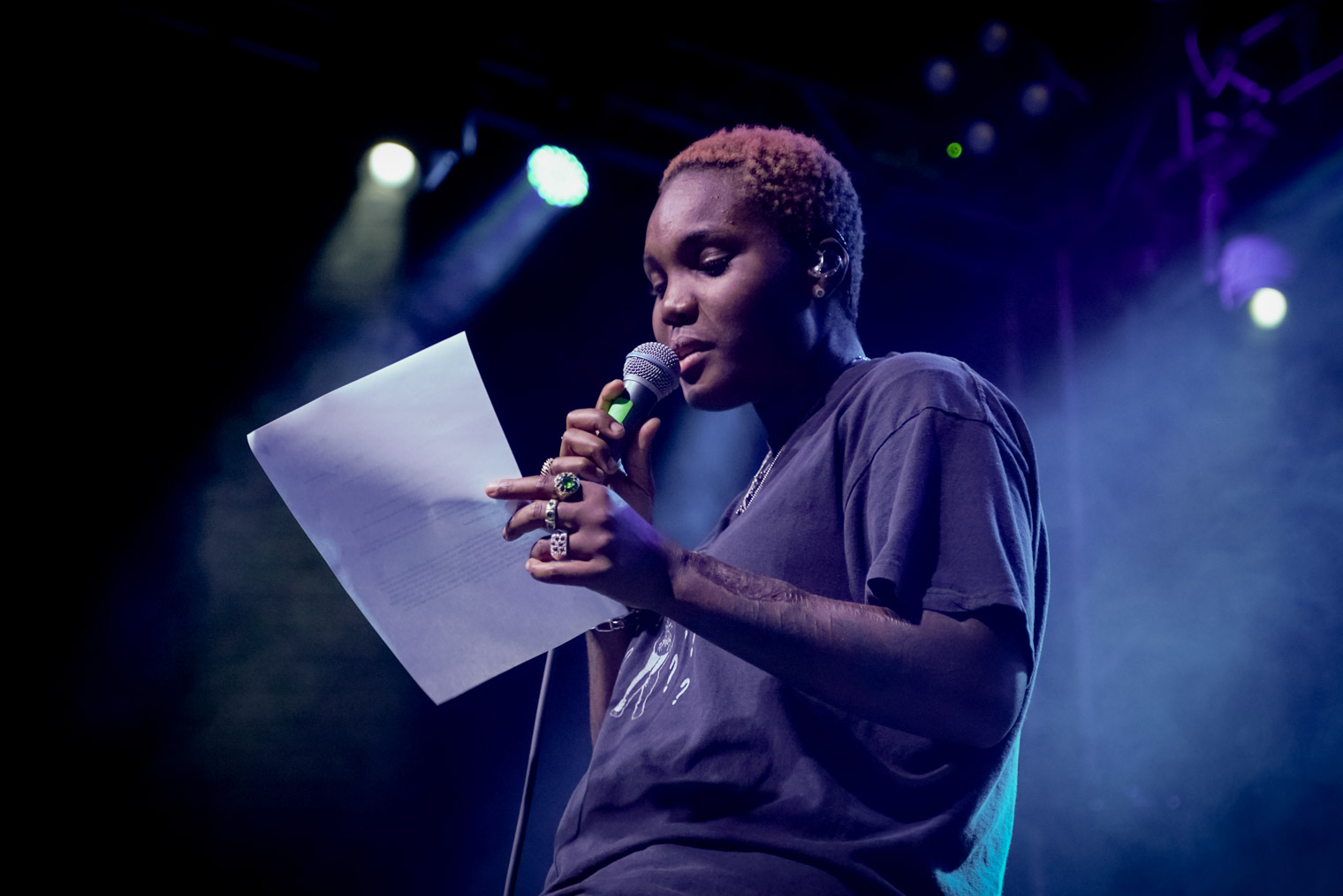 A musician and poet reading a poem on stage