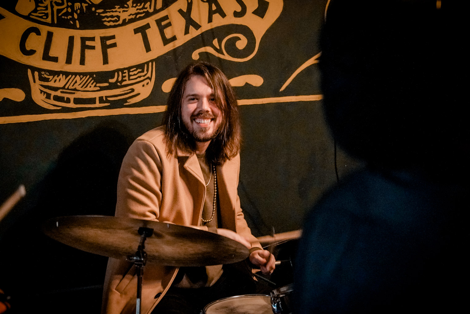 A musician playing drums and smiling