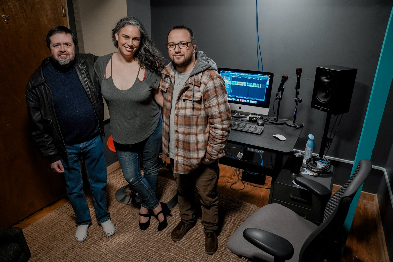 Three people standing inside a recording room