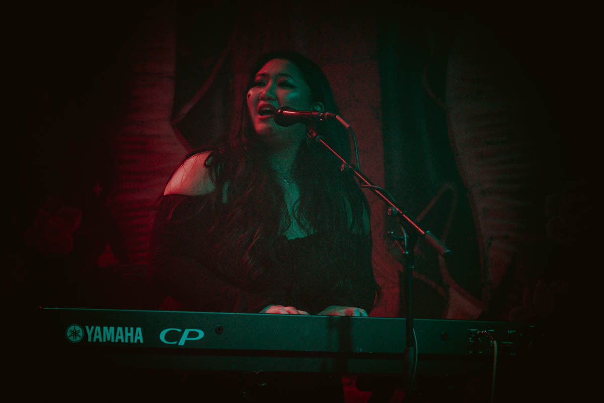 A musician singing on stage and playing piano