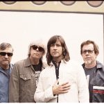 Standing in front of a painted wall, the Old 97s face the camera