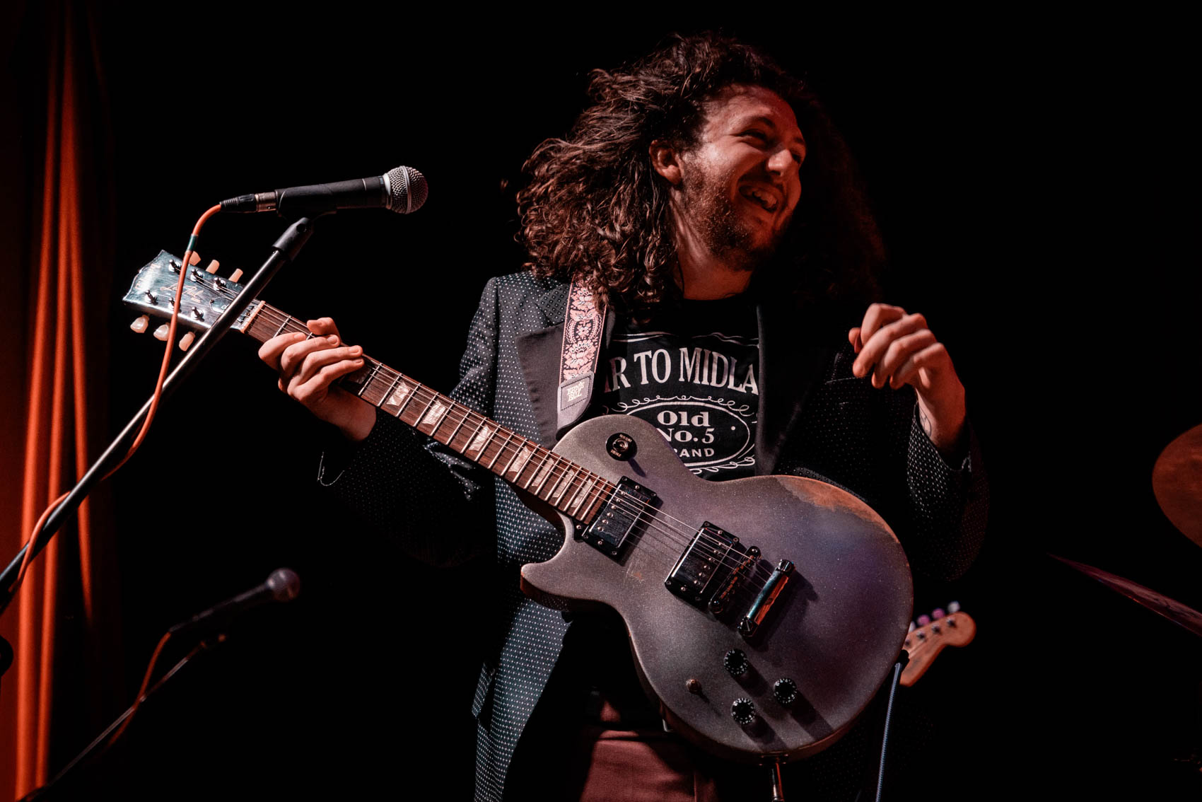 A musician playing guitar and smiling on stage