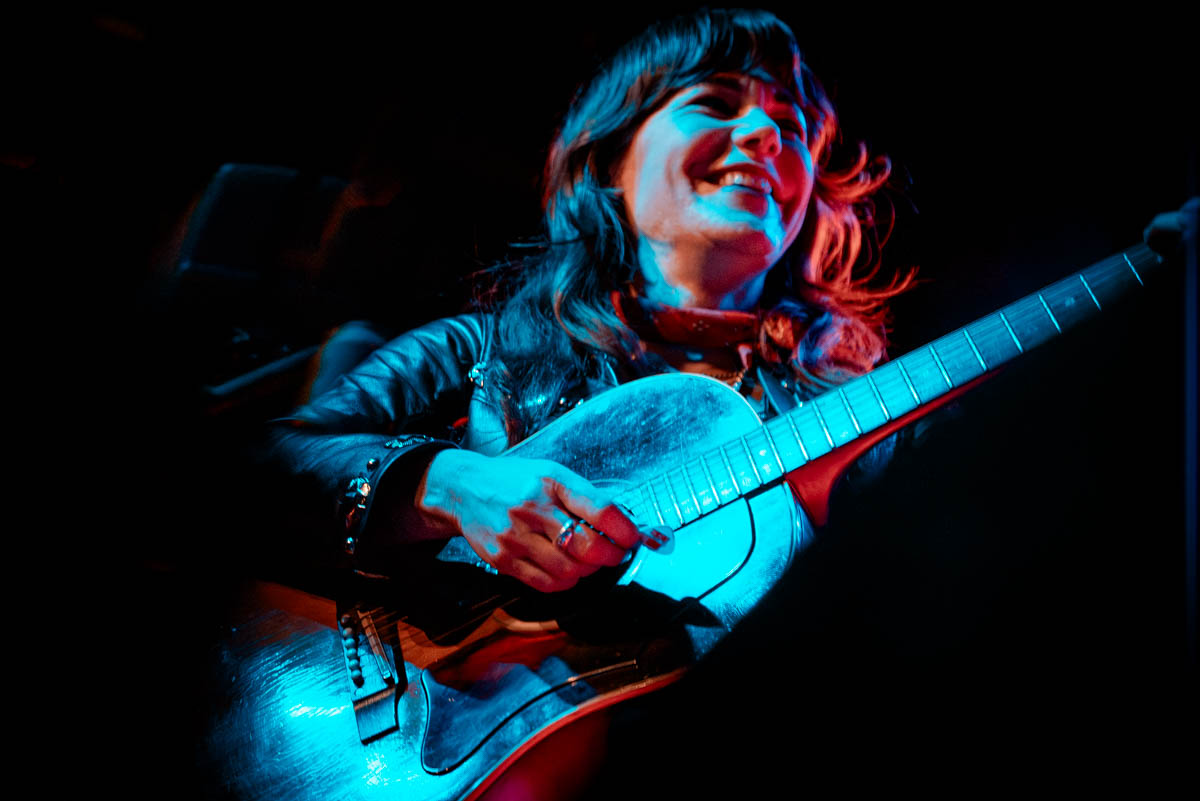 A musician playing guitar and smiling on stage