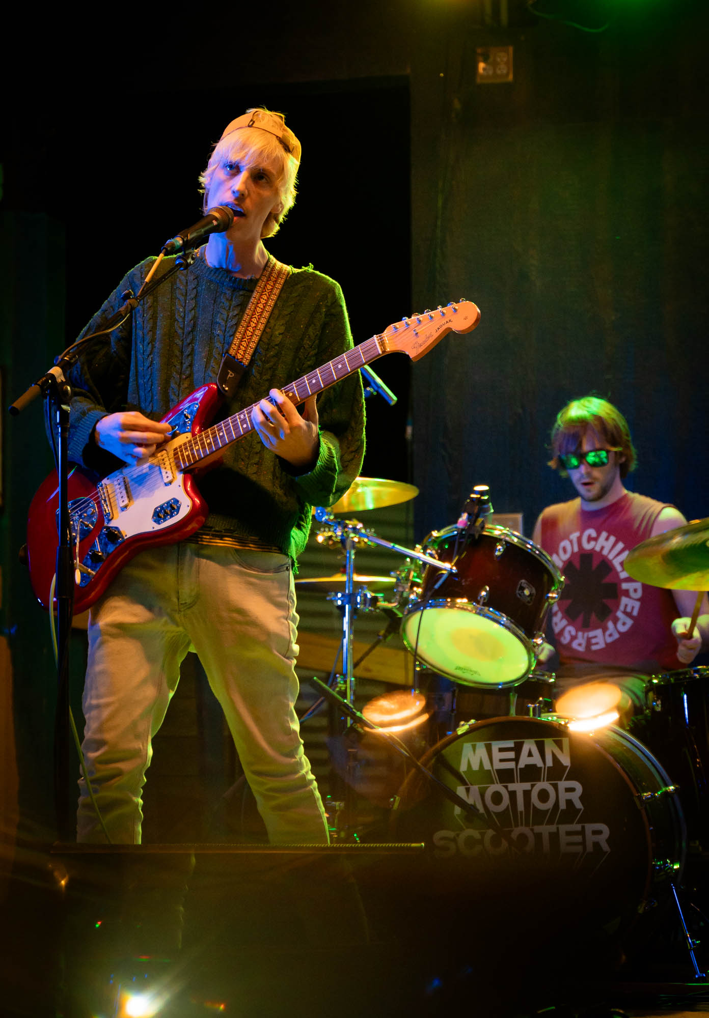 A musician on stage playing guitar and singing and a drummer