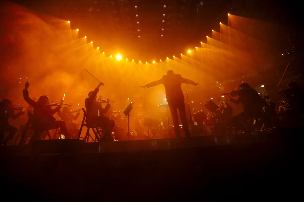A man conducts an orchestra on stage.
